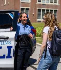 Police officer and student talking next to patrol car.